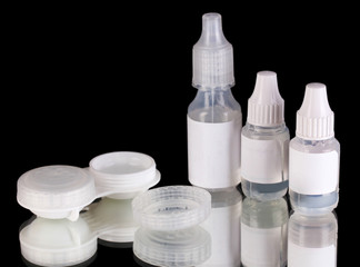 Eye drops and lenses on black background