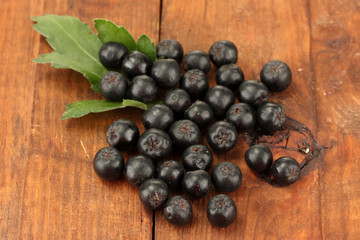 chokeberry with green leaf on wooden background close-up