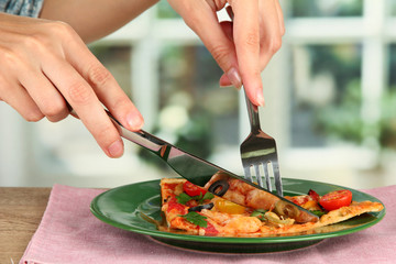 woman's hands cut a slice of pizza close-up