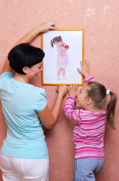 Woman and girl hanging up the picture