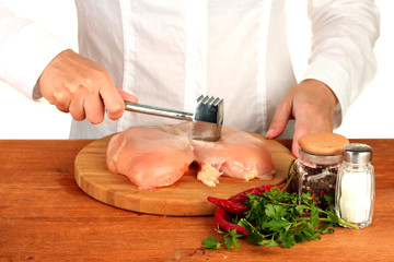 Chef beats meat on wooden table