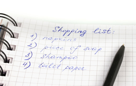 shopping list in a notebook on white background close-up