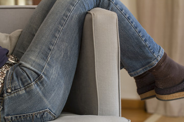 Frau in Hosen lümmelt im Sessel