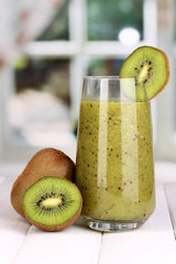 Glass of fresh kiwi juice on wooden table, on window background