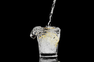 splash in a glass with lemon and ice on a black background