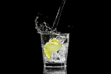 splash in a glass with lemon and ice on a black background