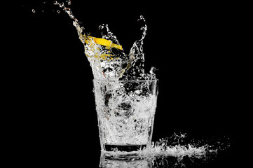 splash in a glass with lemon and ice on a black background