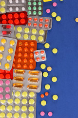 Capsules and pills packed in blisters on blue background