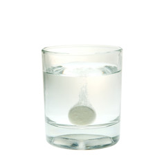 Effervescent tablet splashing into glass isolated on white