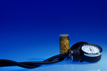 Spyghmomanometer and medicine bottle on blue background