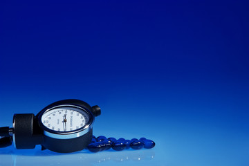 Spyghmomanometer and blue pills on blue background