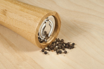 isolated bamboo pepper grinder with grains on the table