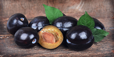 Sweet plums with leaves on wooden tables