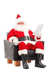 Santa Claus sitting in a comfortable armchair and reading a lett
