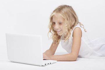 Beautiful blonde little girl in white, with portable computer