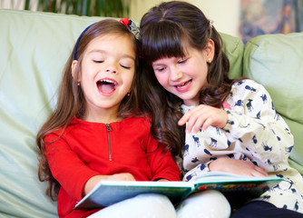 two beautiful girls reading book at home