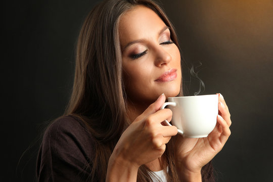 Fototapeta beautiful young woman with cup of coffee on brown background