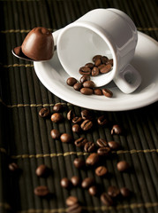 Tazzina caffè con chicchi e cioccolato su sfondo bamboo