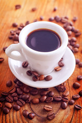 Fototapeta na wymiar fresh coffee in the white cup, coffee beans on wooden background