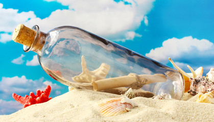 Fototapeta na wymiar Szklana butelka z uwagą wewnątrz na piasku, na niebieskim tle nieba
