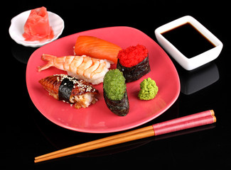 delicious sushi served on red plate isolated on black