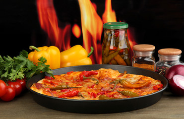 Tasty pepperoni pizza in pan with vegetables on flame