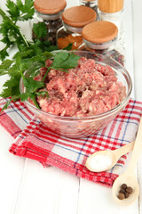 Bowl of raw ground meat with spices on wooden table