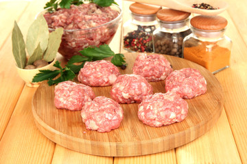Raw meatballs with spices on wooden table