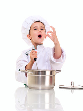 Little singing boy chef in uniform with ladle stiring in the pot