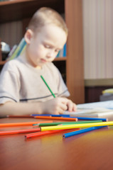 Little boy is learning to draw with pencils (focus on pencils)