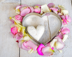White marple heart with rose petals on wooden background