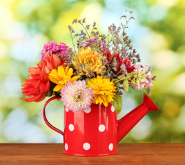 Red watering can with white polka-dot with flowers