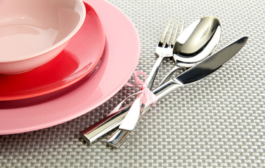 Pink empty plates with fork, spoon and knife