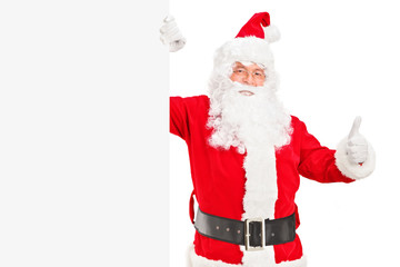 Happy Santa claus standing next to a billboard and giving a thum