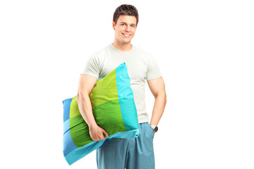 A smiling man in pajamas holding a pillow