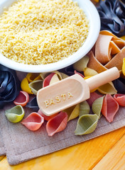 assortment of raw pasta and wheat on wooden background