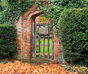 Autumn leaves around a Rustic arched Gate into an English Garden