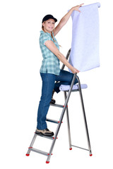 Woman putting up wallpaper