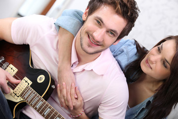 Fototapeta premium Young couple playing a guitar at home