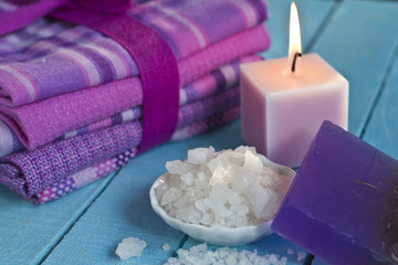 Sea salt in bowl,  lavender soap  with candle and towels on blue