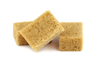 Brown cane sugar lumps on white background
