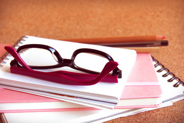Black and purple glasses and some notebooks.