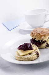 Rosinen Scones mit Himbeermarmelade und Butter auf einem Teller