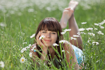 Attractive brunette lying in chamomile field