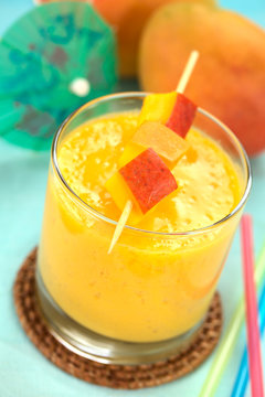 Fresh mango juice in glass with mango pieces on skewer