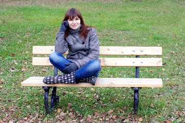 The young woman sits on a bench in autumn park