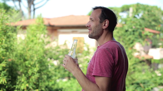 Happy man with beer and cigarette relaxing on his balcony, stead