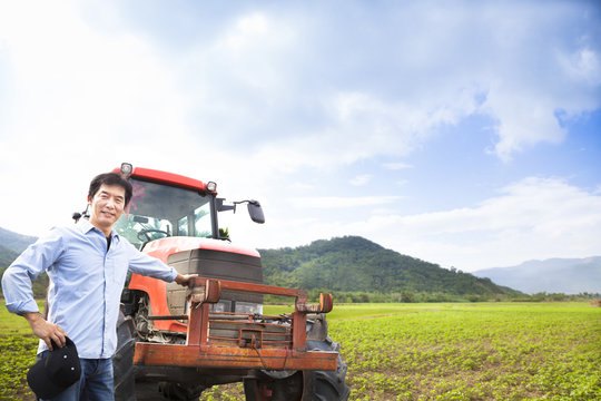 happy asian farmer with Old tractor on the grass field