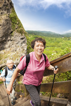 happy asian senior couple hiking in the mountain
