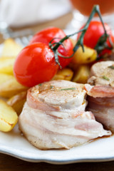 Pork fillet in bacon with cherry tomatoes and baked potato